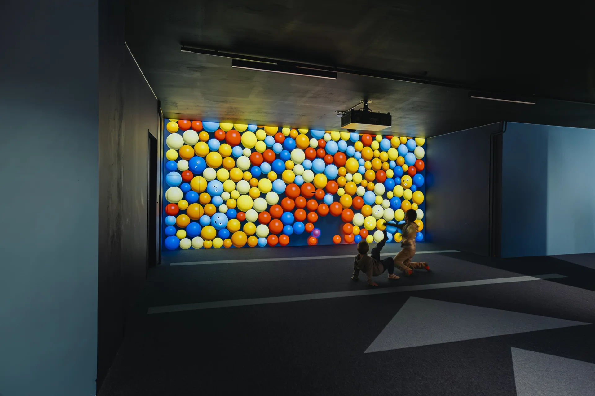 Two children playing against the projected ball wall of Signal Playground